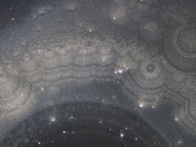 Unos anillos concéntricos formados por motivos claros y oscuros dominan el primer plano y contrastan con un fondo oscuro salpicado.