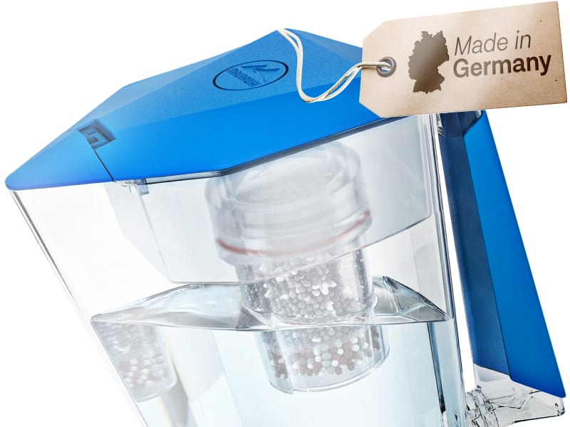 Die Wasserfilterkanne MAUNAWAI Kini in der Farbe Ozeanblau mit einem „Made in Germany“-Etikett, die auf einer transparenten Oberfläche steht.